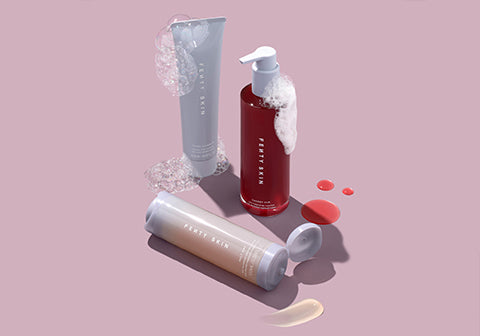 Product shot of Cherry Dub Cleanser, Total Cleanser, and Melt Awf Makeup Removing cleanser covered with soap suds on a lavender background. Product shot of Cherry Dub Cleanser, Total Cleanser, and Melt Awf Makeup Removing cleanser covered with soap suds on a lavender background.